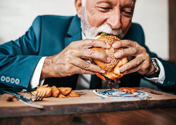 Old fashionable man eating a delicious hamburger